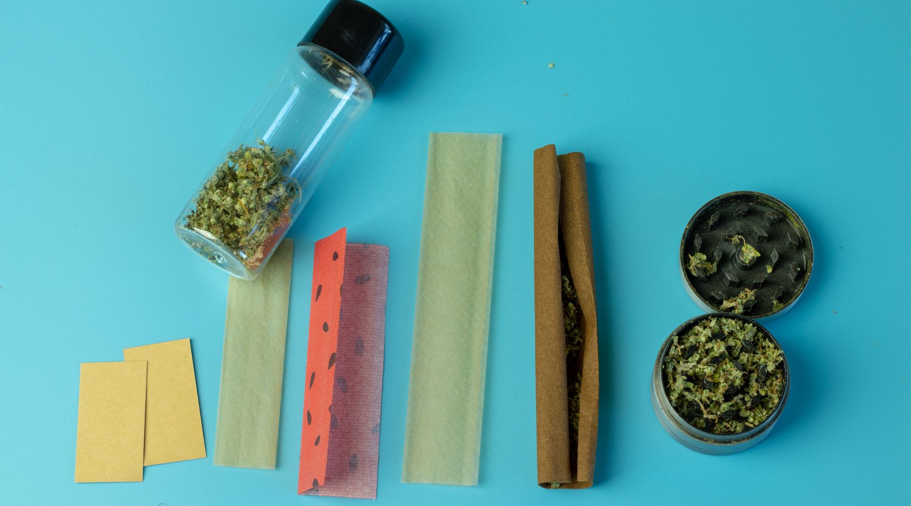 hemp-derived delta-9 THC flower in a vial on a blue background next to smoking and rolling accessories